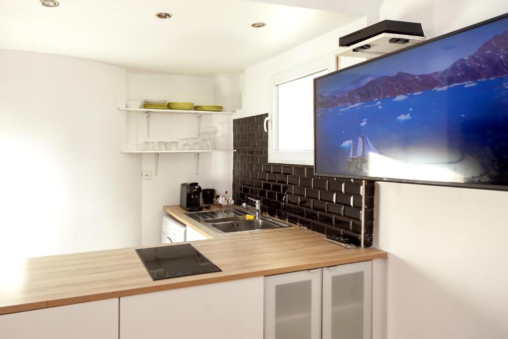 Il comprend une cuisine avec un évier et une télévision murale. dans l'établissement Charmant appartement - 4 couchages à proximité d'Opéra et des métros, à Paris
