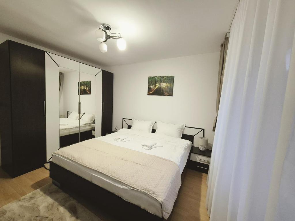 a bedroom with a white bed and a mirror at Apartament Verde Residence Slănic-Moldova in Slănic-Moldova