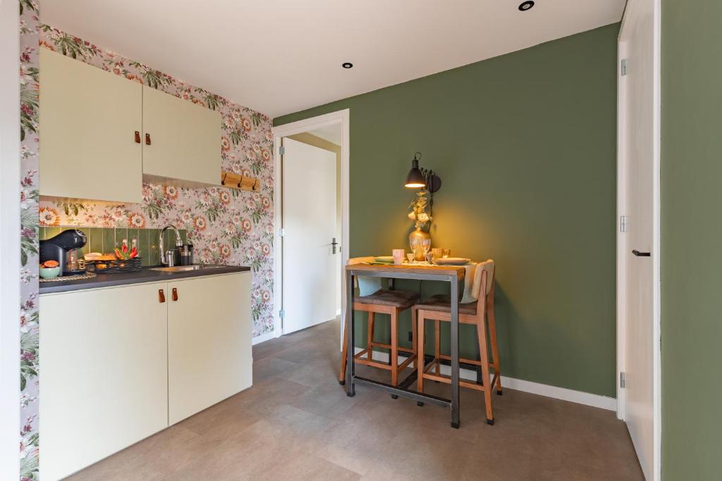 a kitchen with green walls and white cabinets at B&B de Groene Poort in Stein