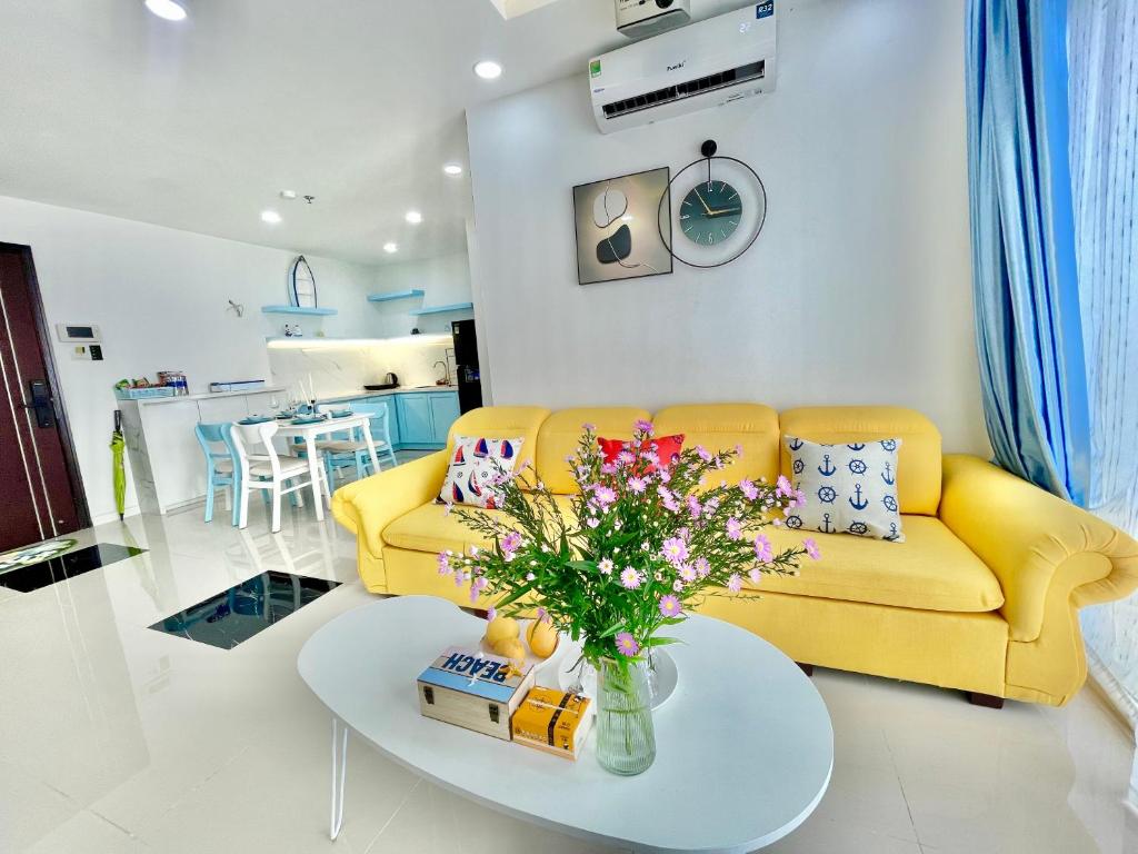 a living room with a yellow couch and a table at 2BR Luxury riverview - Melody of the Sea Monarchy in Da Nang