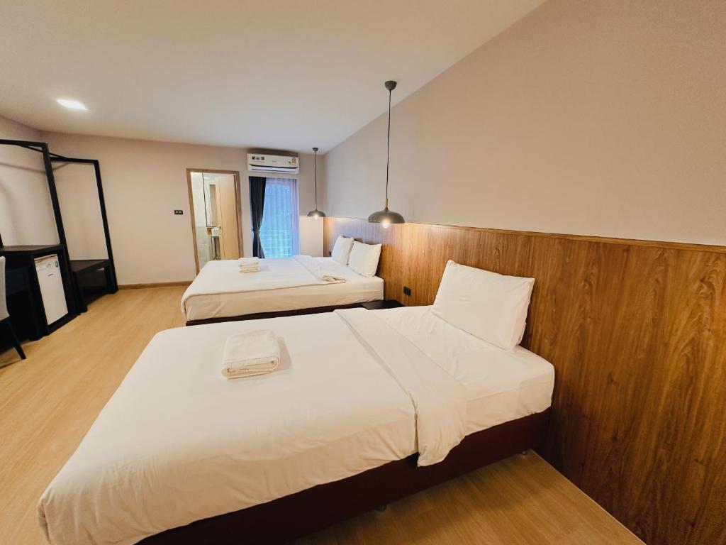 Una habitación de hotel con dos camas con sábanas blancas. en Common Living, en Chiang Mai