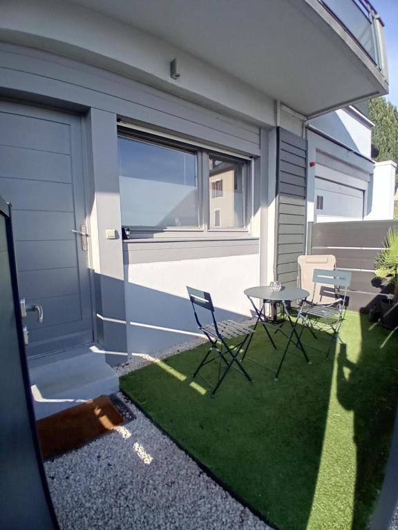 un patio avec des chaises et une table en face d'un garage dans l'établissement Appart paisible, propre et accueillant, à Pers-Jussy