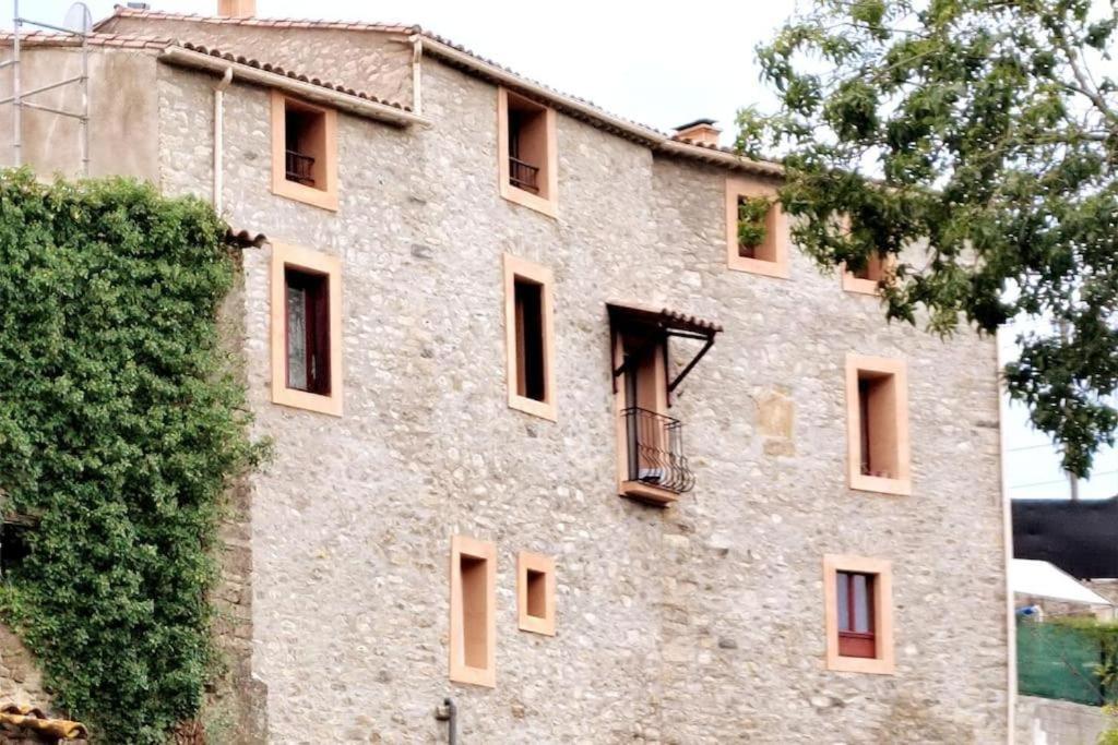 - un grand bâtiment en pierre avec des fenêtres et un arbre dans l'établissement Chambres doubles, à Antugnac
