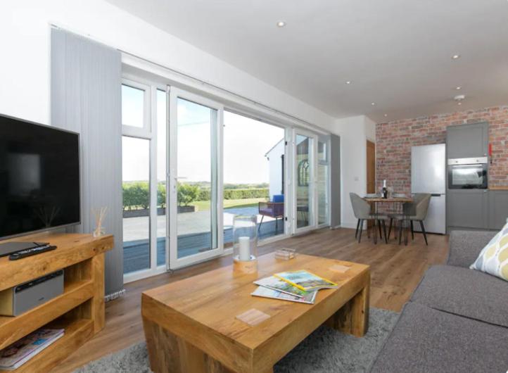 ein Wohnzimmer mit einer Couch, einem Fernseher und einem Tisch in der Unterkunft Adorable 1 bedroom Country Cottage in Bodewryd