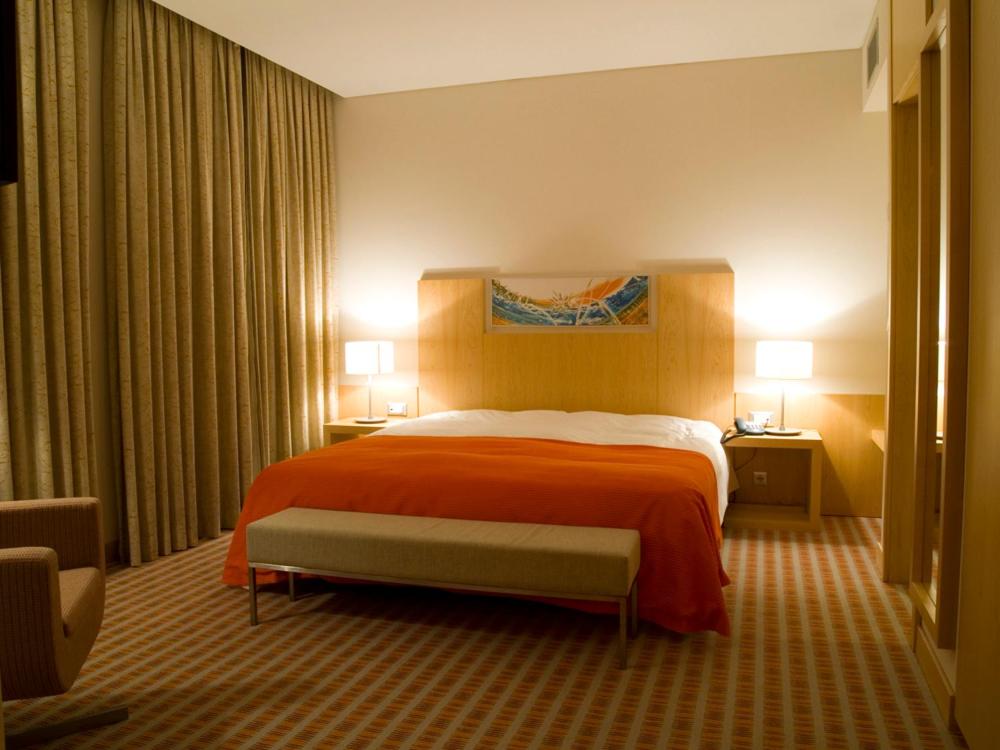 a hotel room with a large bed with orange sheets at Hotel Praia in Nazaré