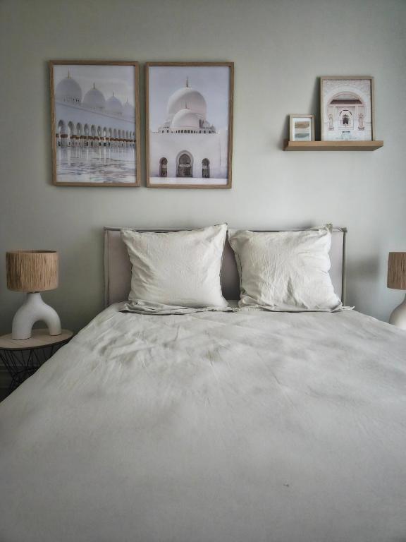 une chambre avec un lit avec deux tableaux au mur dans l'établissement Le cocon du voyageur, à Bruay-la-Buissière