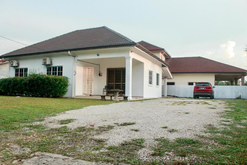 a white house with a car parked in front of it at Kundang Villa @ Tasik Biru - 3 Bedrooms Bungalow in Rawang