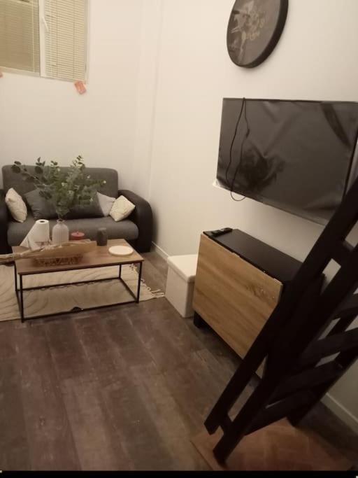 un salon avec un canapé et une horloge au mur dans l'établissement Appartement sur mezzanine, à Villetaneuse