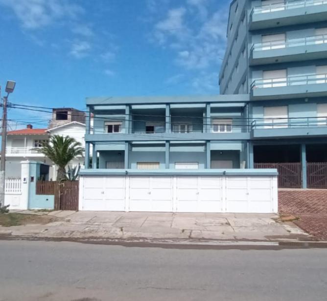 ein Apartmenthaus mit einem weißen Zaun davor in der Unterkunft Vila Gesell, zona centro y playa in Villa Gesell