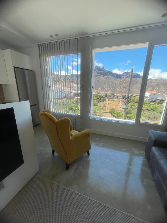 a living room with a yellow chair and large windows at Ventana del Nublo 2-D in Tejeda