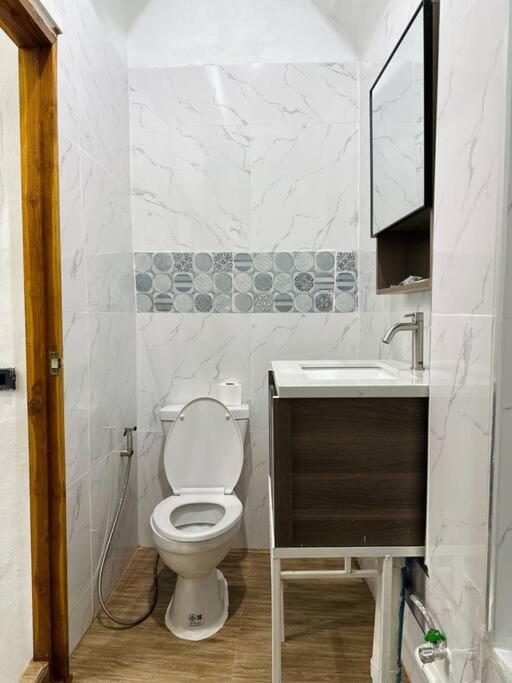 a white bathroom with a toilet and a sink at Megun 10 Duplex in Bangkok