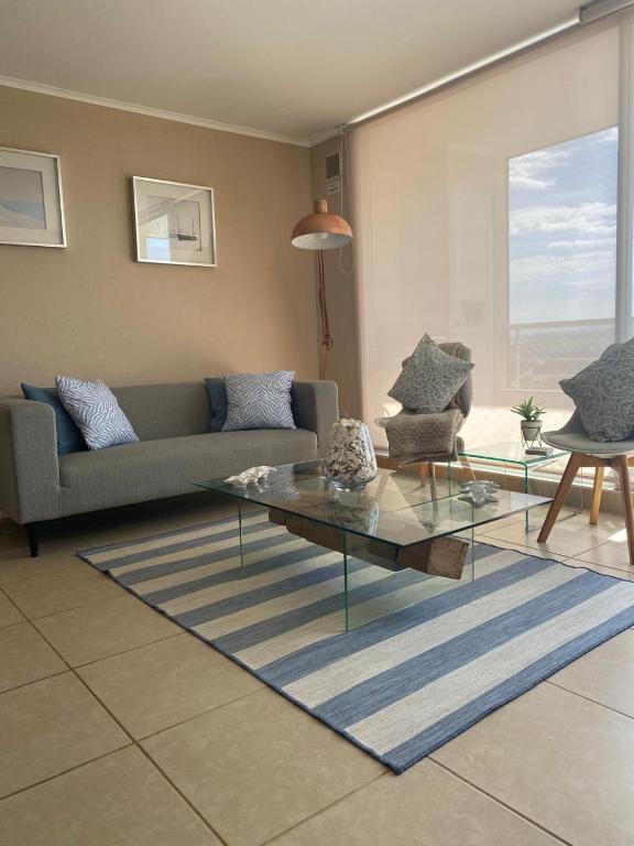 a living room with a couch and a glass table at Resort Laguna Bahía, Océano Piso 12 Algarrobo in Algarrobo
