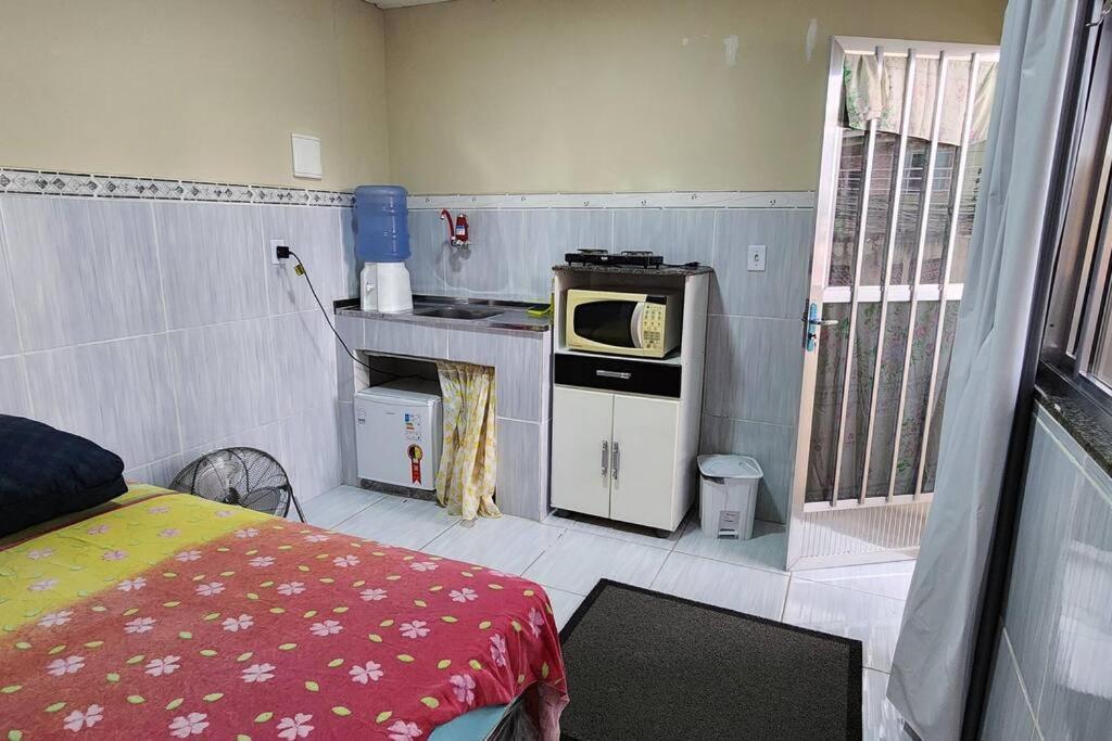 a small kitchen with a bed and a microwave at Kitnet alojamento independente in Nova Iguaçu