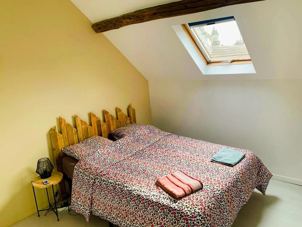 a bedroom with a bed with a table and a window at La perle rare Chambly, Proche Parc Astérix , château de Chantilly in Chambly