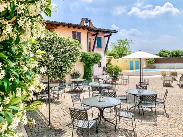 a patio with tables and chairs and an umbrella at Corte Uccellanda Relais & Spa in Monzambano