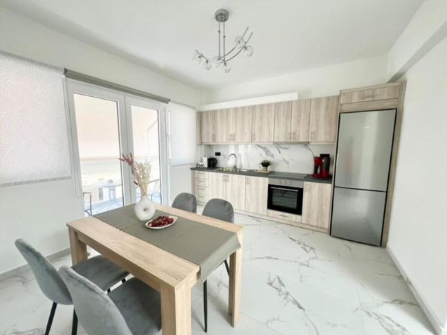 une cuisine avec une table, des chaises et un réfrigérateur dans l'établissement Ionia's Comfort Appartments -2nd floor, à Athènes