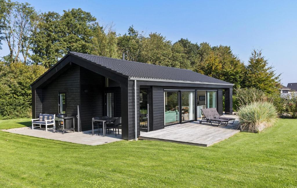 a black cabin with a deck in a yard at 3 Bedroom Amazing Home In Sydals in Sarup