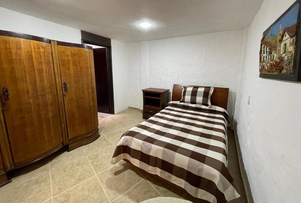 a bedroom with a bed and a wooden cabinet at Alojamiento 1A Amplia Habitación Independiente in Cota