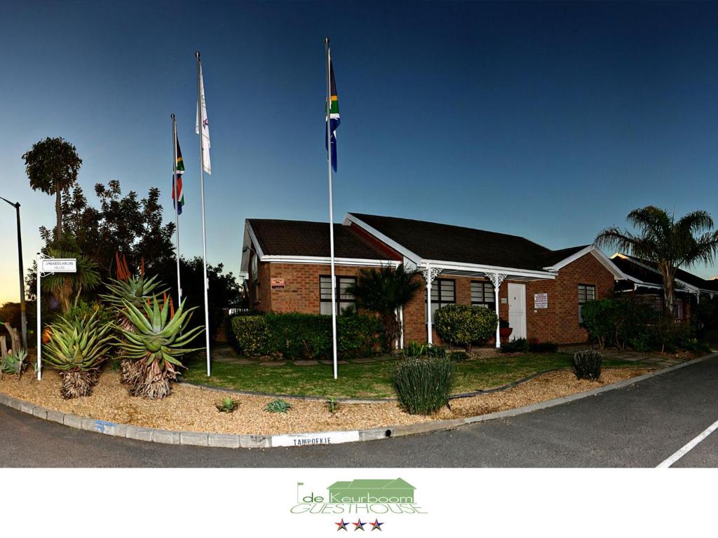 two flags on poles in front of a house at De Keurboom Guesthouse in Kuilsrivier