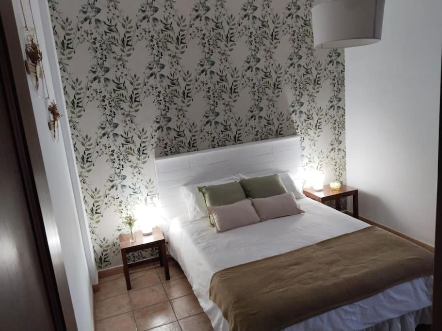 a bedroom with a bed with two pillows and wallpaper at La Perla, vivienda vacacional in Garachico