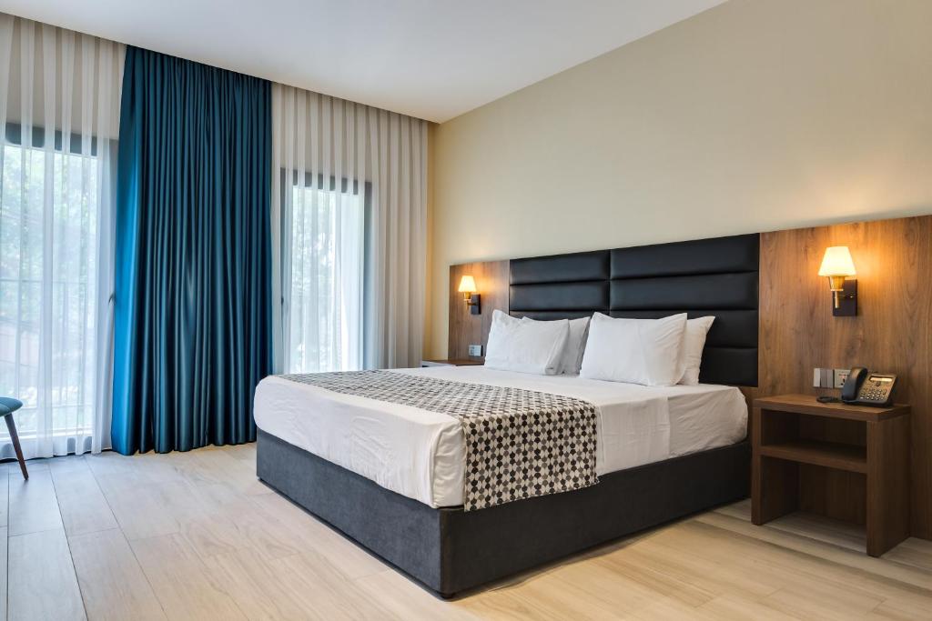 a hotel room with a large bed and windows at Eleven Inn Apartments Tbilisi in Tbilisi City