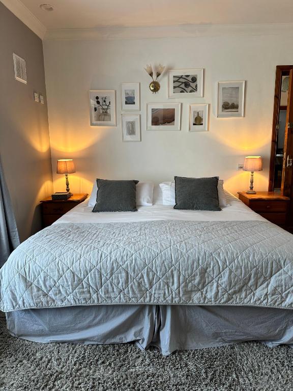 a bedroom with a bed with two lamps and pictures on the wall at Malahide Guest Rooms in Malahide