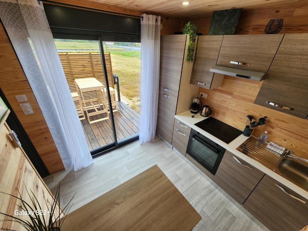 une cuisine avec des placards en bois et une grande fenêtre dans l'établissement Le Cozy Cottage - Chalet avec parking, à Châtillon-sur-Cher