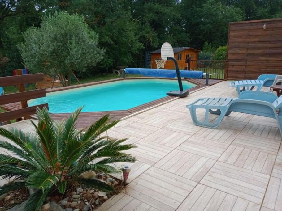 - une piscine avec des chaises bleues sur une terrasse en bois dans l'établissement Maison de campagne avec piscine proche Carcassonne, à Raissac-sur-Lampy