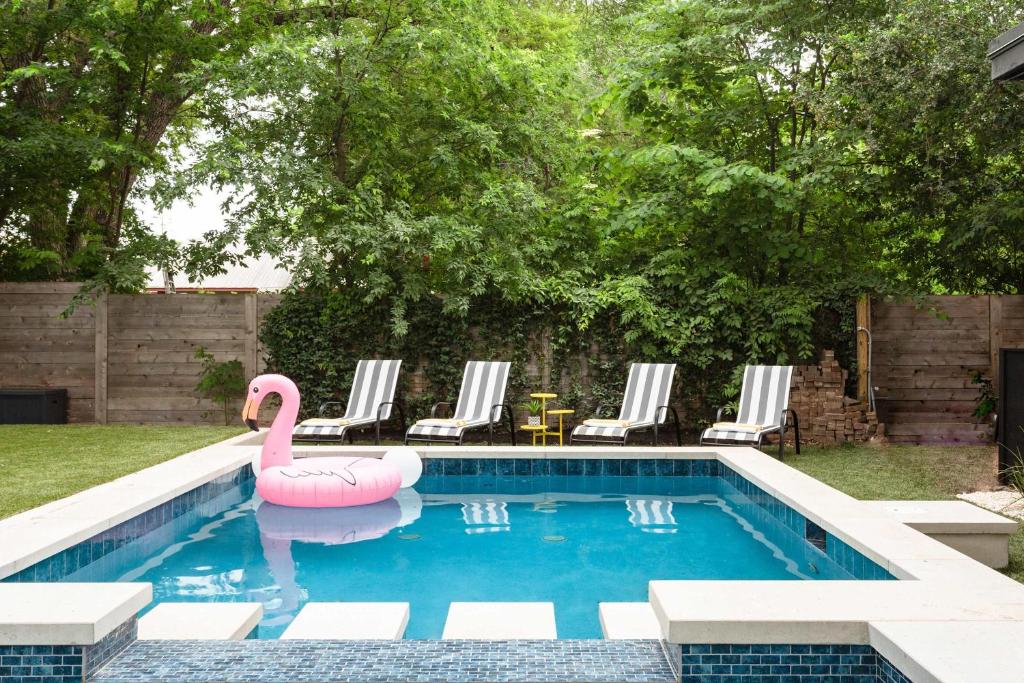 a swimming pool with a pink swan in the water at Pristine Pool Palace 6BR - Rainey St - 7min walk in Austin