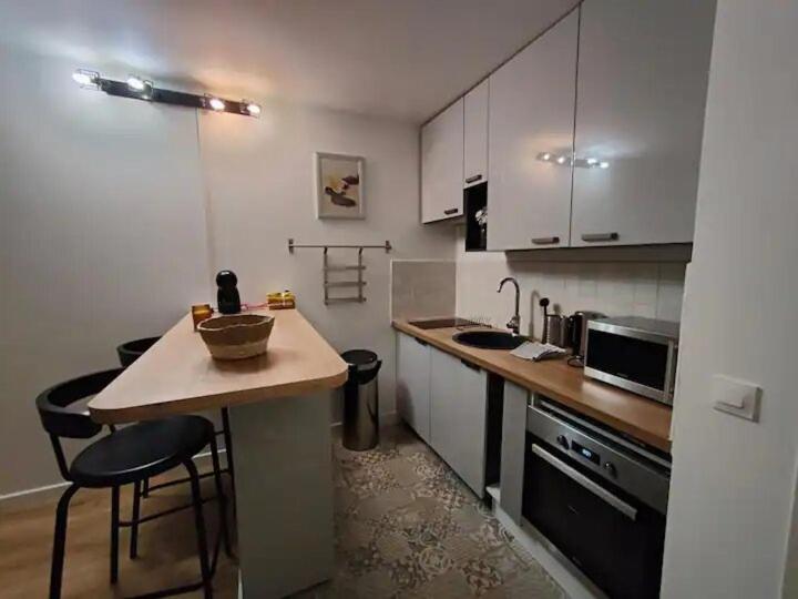 a kitchen with a counter and some chairs in it at Charmant studio in Roissy-en-France