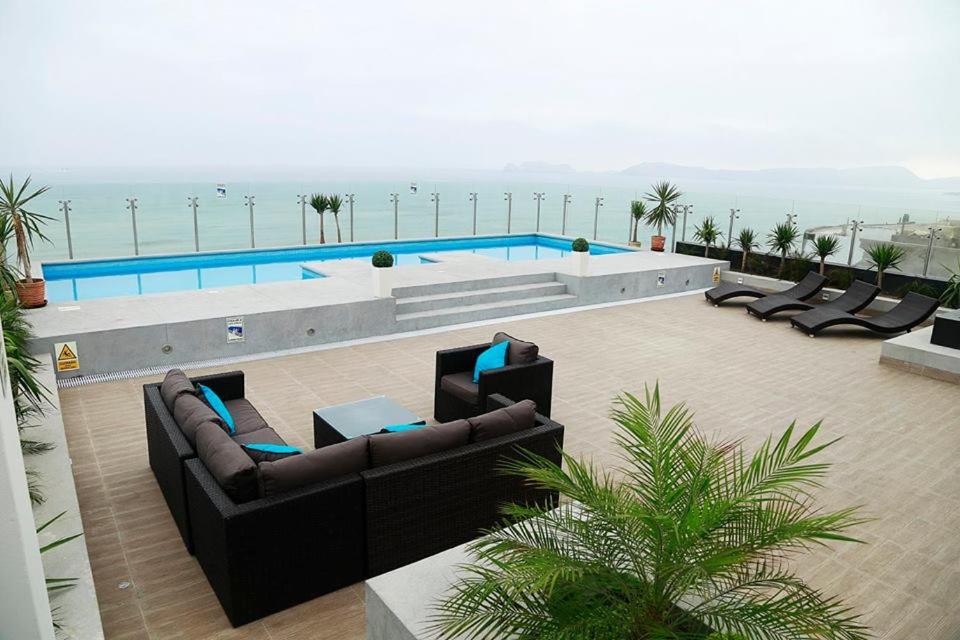 - une piscine avec des canapés et des chaises à côté de l'océan dans l'établissement Lima Flats 2, à Lima