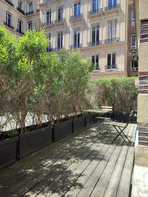 une cour avec des tables et des arbres devant un bâtiment dans l'établissement Beautiful apartment with terrace in Paris 8, à Paris