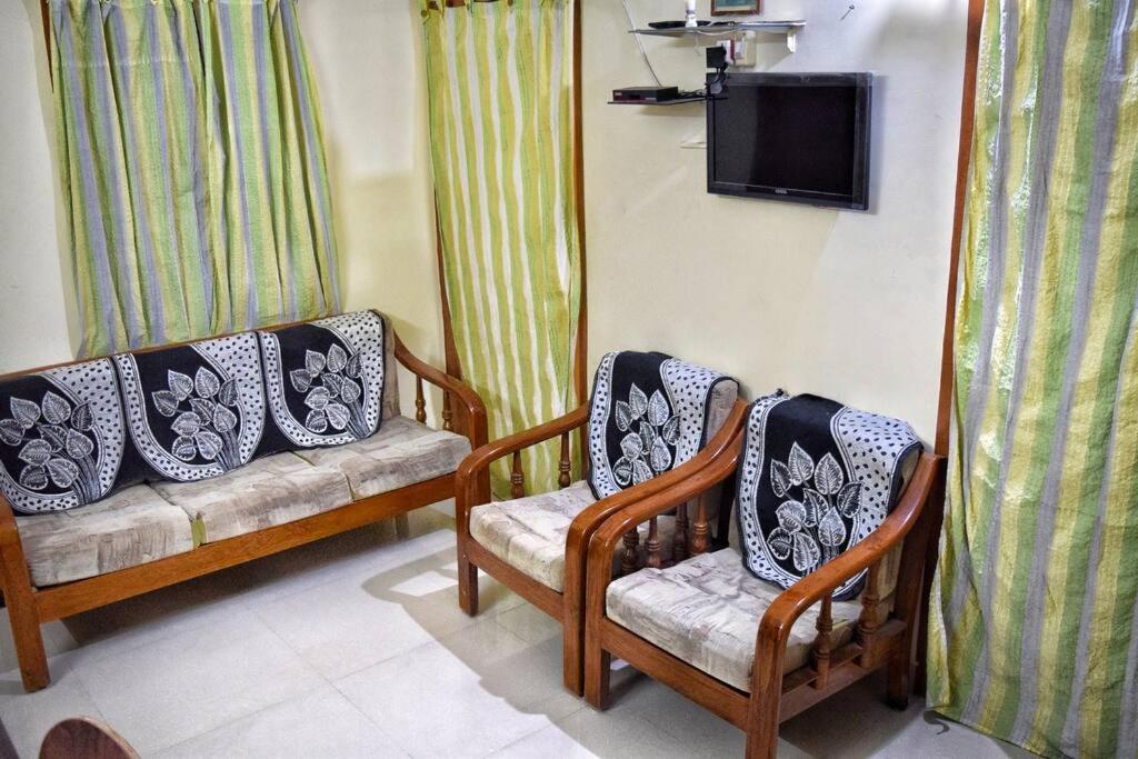 a living room with two chairs and a tv at Charisma Homestay in Mangalore