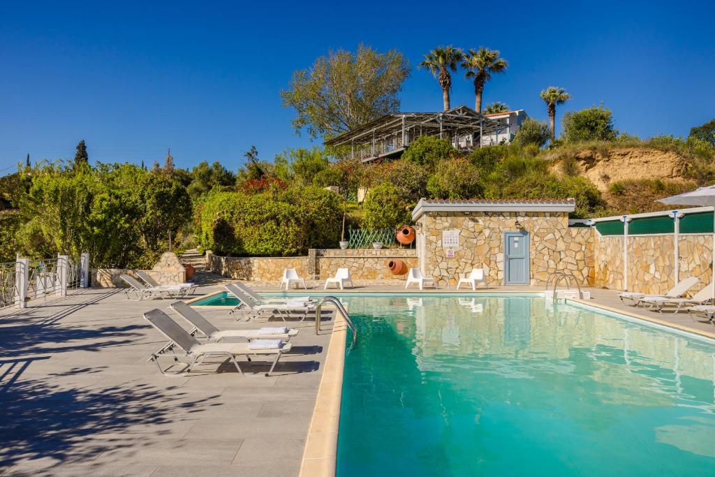 a swimming pool with lounge chairs and a house at Costa Avithos in Svoronata
