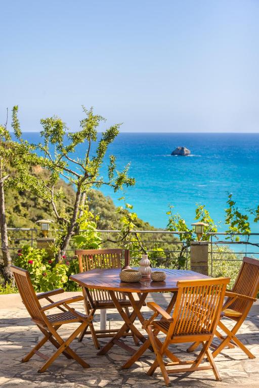 a wooden table and chairs with a view of the ocean at Costa Avithos in Svoronata