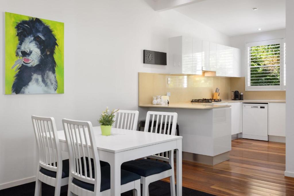 a kitchen and dining room with a white table and chairs at Lane by the Bay - Centrally located 2 bed modern Townhouse in Byron Bay