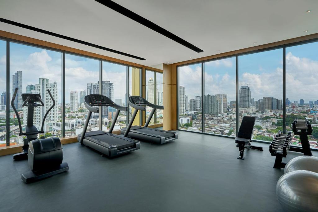 A bright fitness room with cardio machines, weights, and expansive city views.