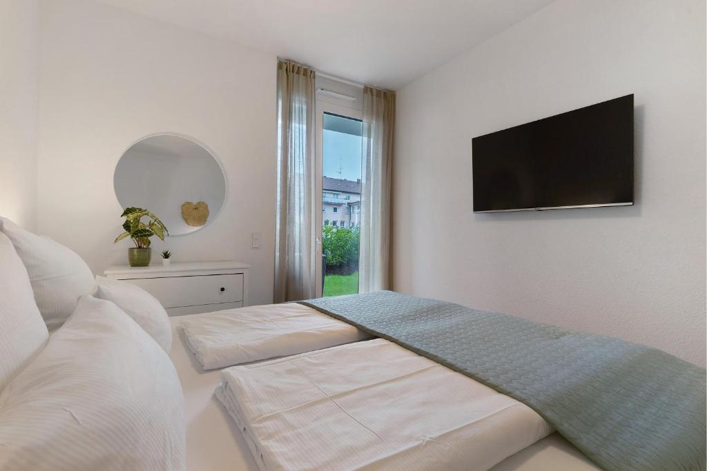 1 dormitorio blanco con TV de pantalla plana en la pared en Km Style Apartment Nr 2, en Freiburg im Breisgau