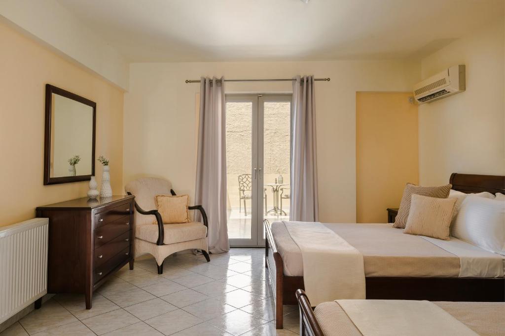 a bedroom with a bed and a chair and a window at Belle View Hotel - Sea View & Sunset in Mánganos