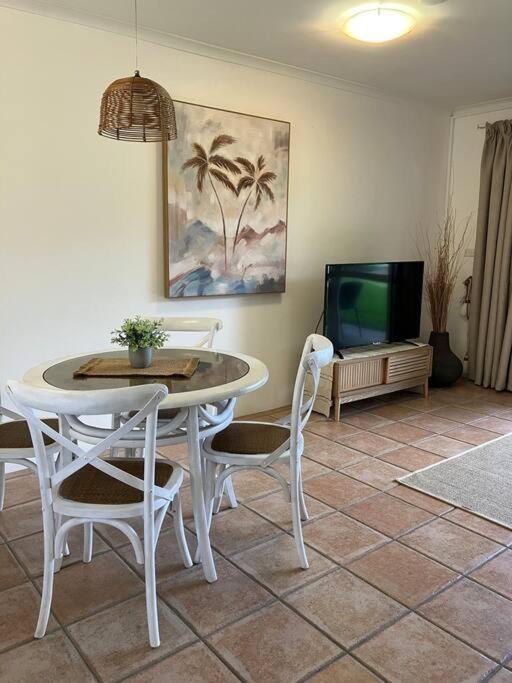 a living room with a table and chairs and a tv at Casa Palma in Palm Cove