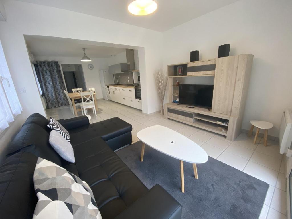 ein Wohnzimmer mit einer schwarzen Couch und einem Tisch in der Unterkunft Maison rénovée avec cuisine équipée à La Roche-Posay - FR-1-541-148 in La Roche-Posay