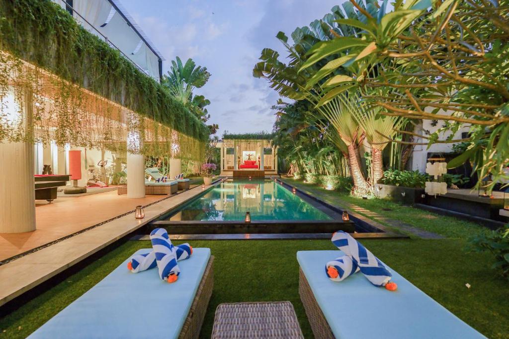a pool in a building with two dogs sitting on benches at Da Vinci The Villa by Nagisa Bali in Tumbak Bayuh