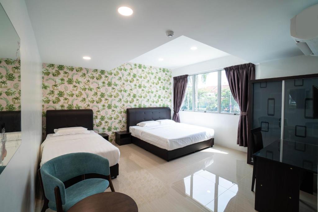 a bedroom with two beds and a table and a chair at Crystal Garden Hotel (Tasik Selatan) in Kuala Lumpur