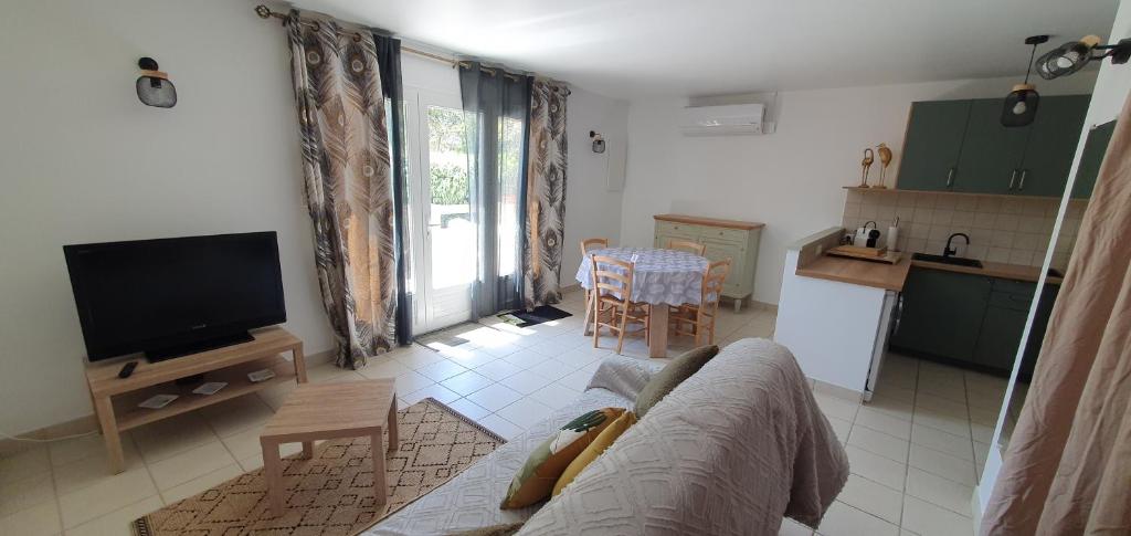 un salon avec un canapé et une télévision et une cuisine dans l'établissement Mini villa - T2 climatisé, proche des plages, à Eccica-Suarella