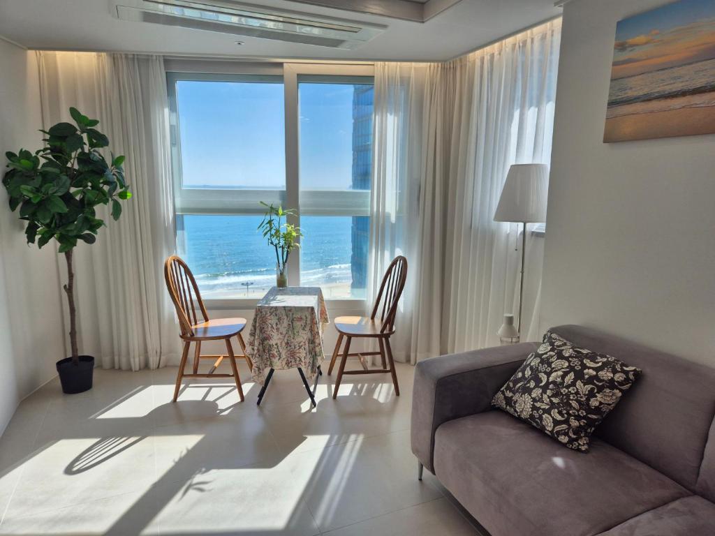 a living room with a couch and a table and chairs at Hotel Irua Haeundae in Busan