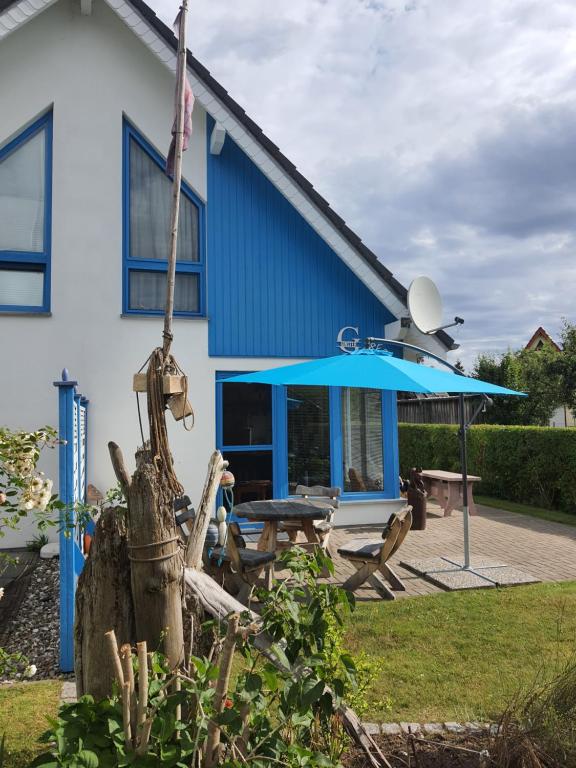 a blue house with a picnic table and an umbrella at Ginster in Zingst