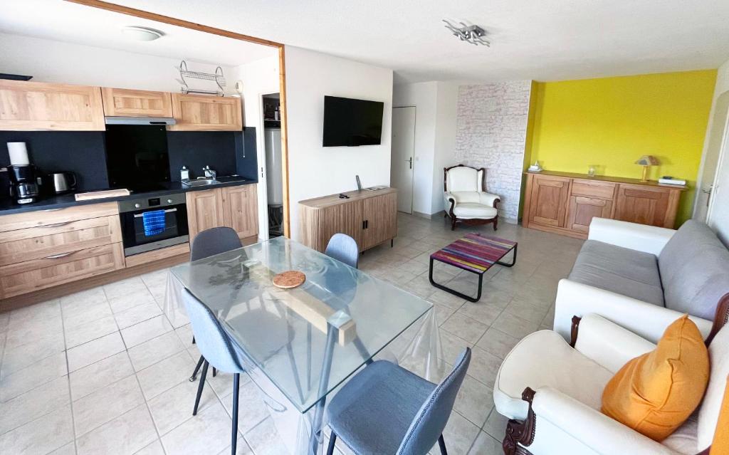 a living room with a glass table and a kitchen at Les boucaniers in Berck-sur-Mer