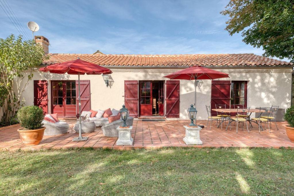 a patio with red umbrellas and a table and chairs at Le Gîte du Château de la Vérie in Challans