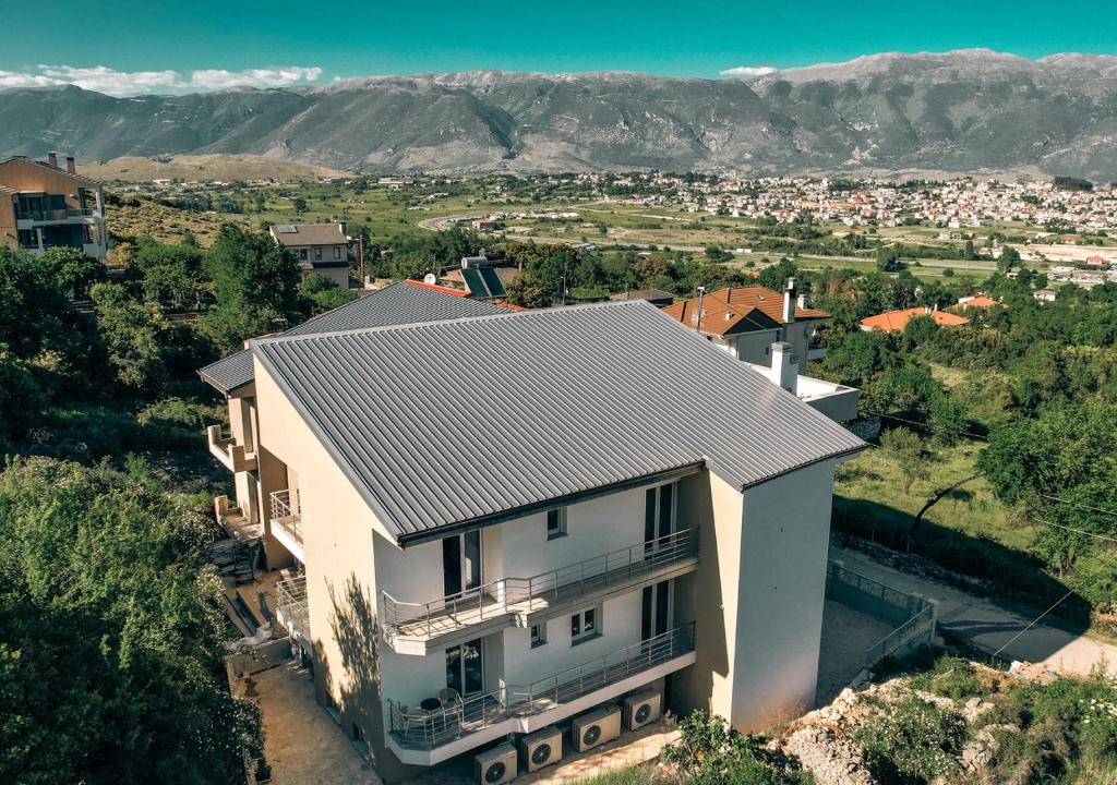 an aerial view of a white house with mountains in the background at Olympiada Suites in Ioannina