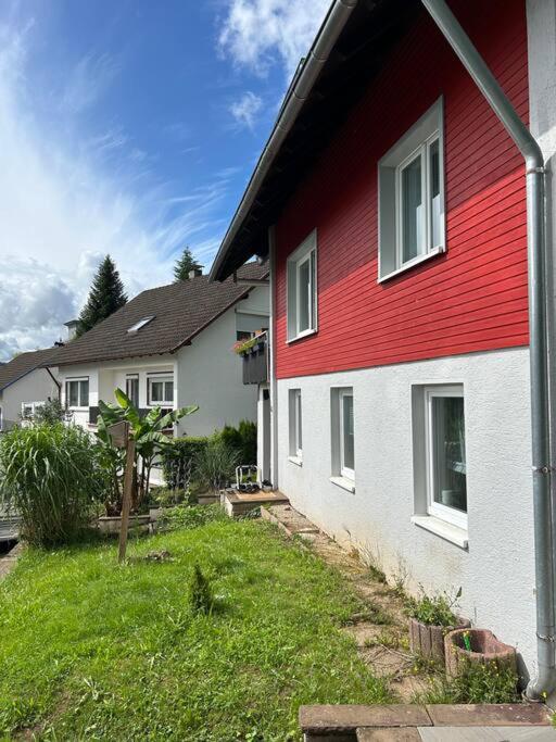 a red and white house with a grass yard at Ferienwohnung in Alpirsbach in Alpirsbach